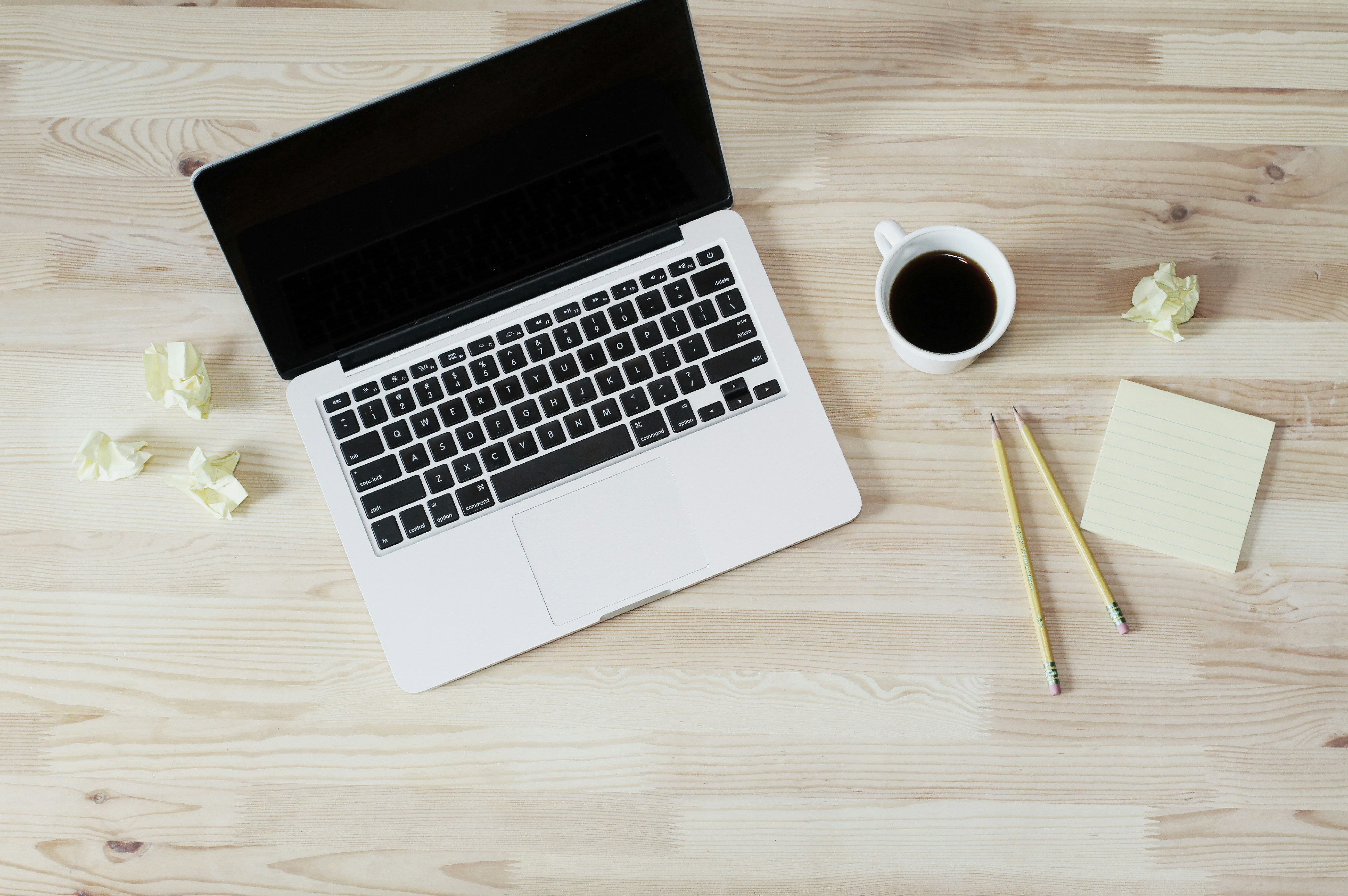 Ordinateur portable sur un bureau en bois, avec café et bloc-notes